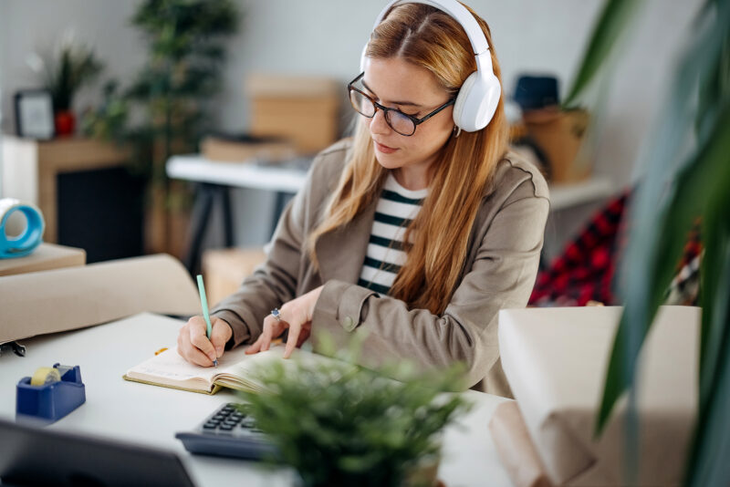 Woman writes down the order Woman writes down orders while working in her home office