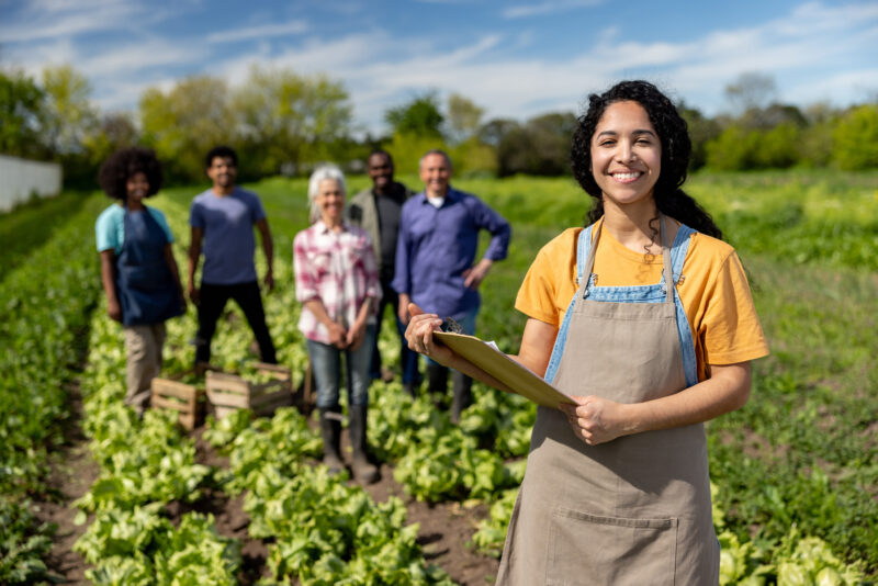 Female worker leading a group of farmers working at a plantation Happy female worker leading a group of farmers working at a plantation - agricultural activity concepts