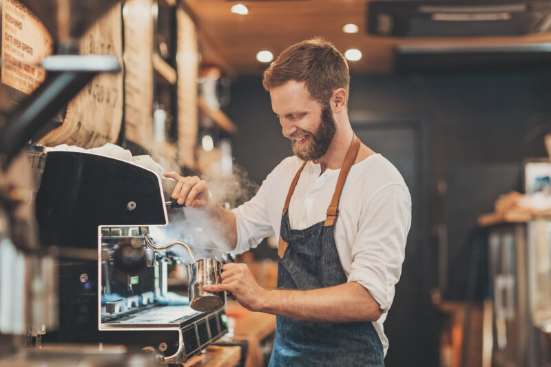 Male barista making cappuccino Smiling male barista preparing cappuccino in a coffee shop