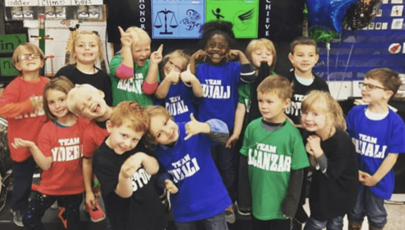 A picture of young students smiling in their classroom having the BEST day ever.