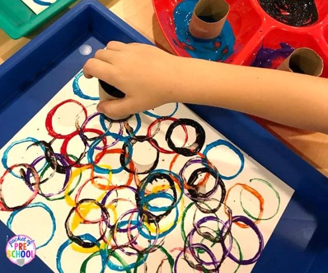 Kindergarten Art Projects Pocket of Preschool A child's hand is seen making circle prints with a toilet paper roll and paint in this example of kindergarten art projects.