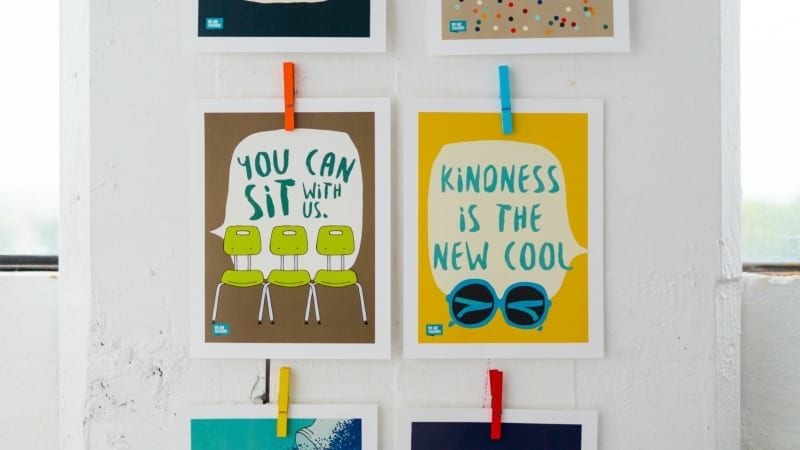 Hanging posters that say "You can sit with us" and "kindness is the new cool"