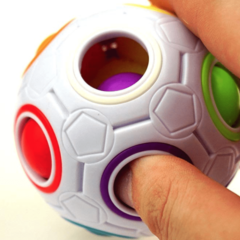Screen Shot 2018-10-19 at 11.27.13 AM Student playing with a white plastic ball with holes filled with smaller colorful rubber balls