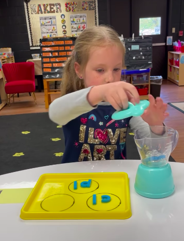 Child using a toy blender and magnetic letters to practice consonant blends to help answer "What is Phonics?"
