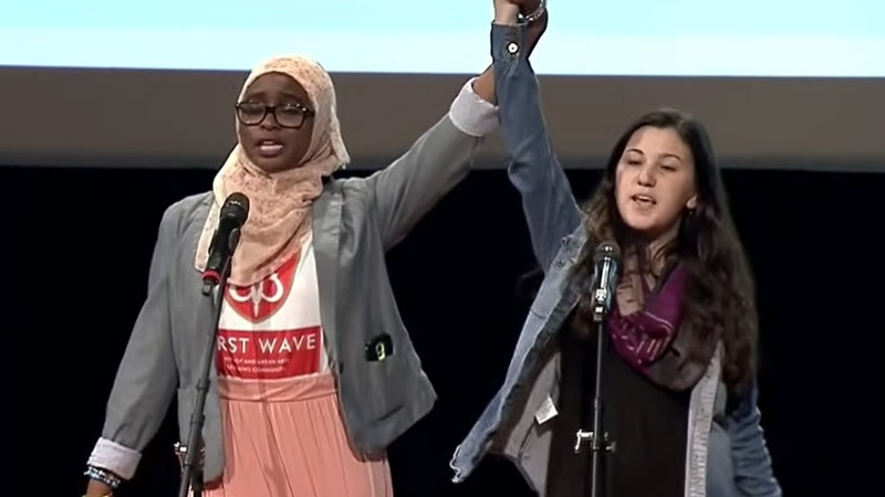 A Muslim girl and a Jewish girl reciting their composition at a poetry slam (Slam Poetry Examples)