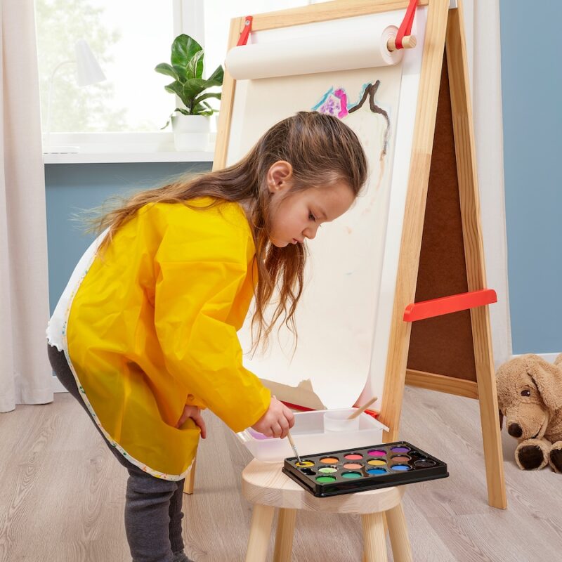 Smock A little girl in a yellow smock stands before an easel painting.