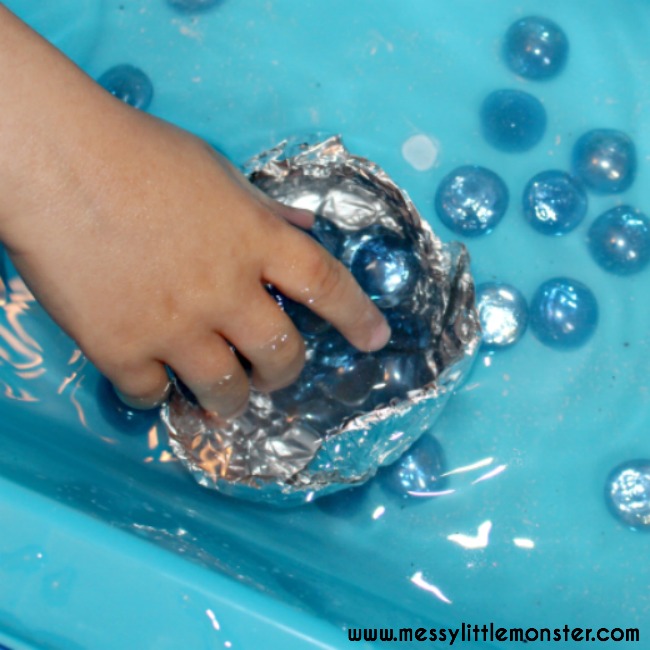 aluminum-foilboat A hand places blue gems into a boat made from aluminum foil in a tub of water
