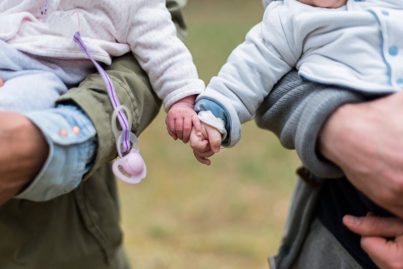 Writing Prompts: Baby Friends Two babies holding hands while being held by adults