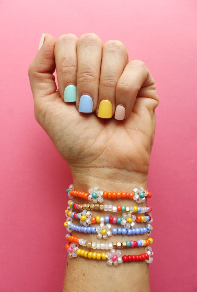 beaded-daisy-chain A hand with painted nails shows off a pretty stack of beaded bracelets