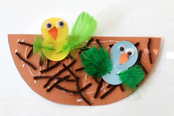 birds-nest Two baby birds made from construction paper and feathers sit atop a nest as an example of summer crafts for kids
