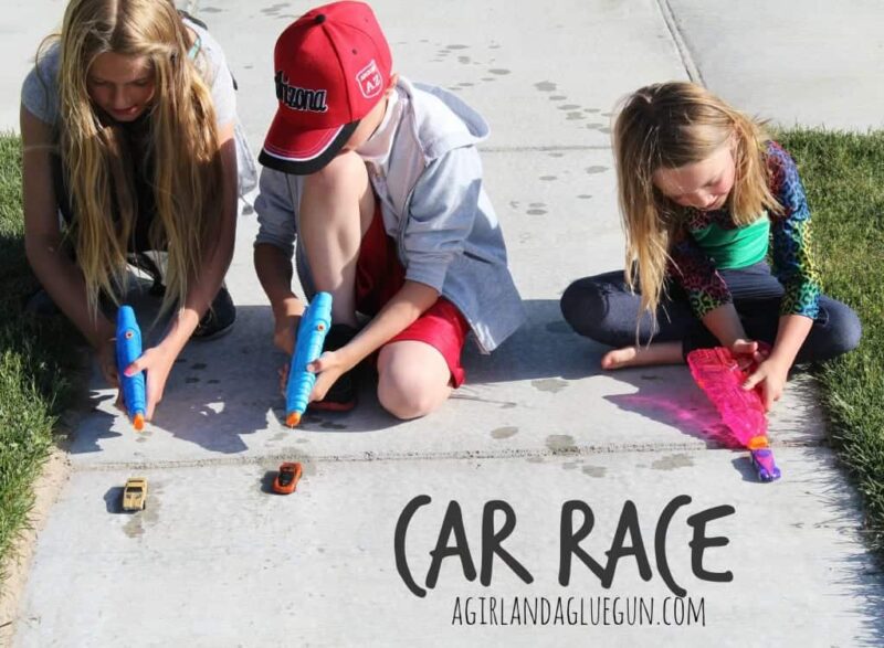 car-race child using squirt gun to push a car down the sidewalk