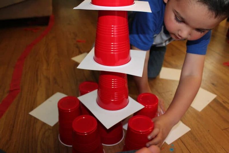 Cup Stacking STEM Challenge Preschooler making a stack of red plastic cups and index cards