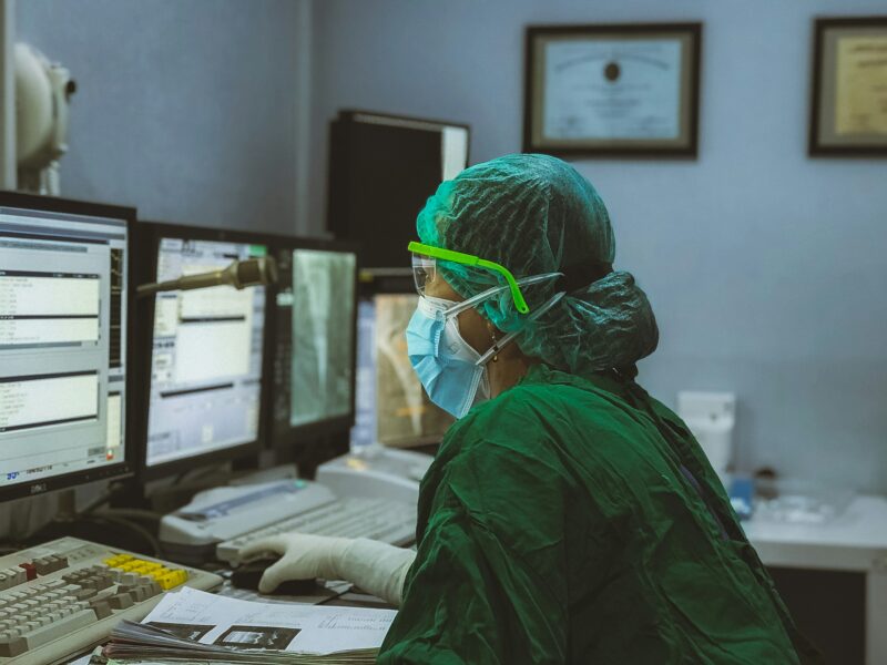 A person wearing scrubs and a medical map consults data on a computer