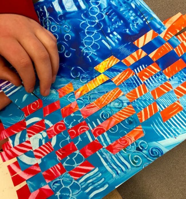 Fifth Grade Art Paste Paper Weaving Student weaving together two pages painted in different patterns (Fifth Grade Art)