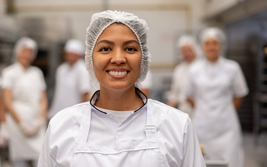 fast food worker Happy female employee working at a food factory and looking at the camera smiling