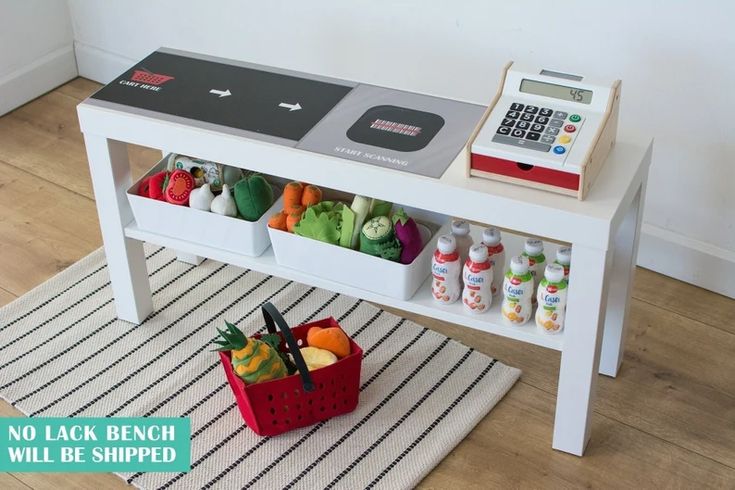 A play grocery store checkout is shown with a basket of toy groceries.