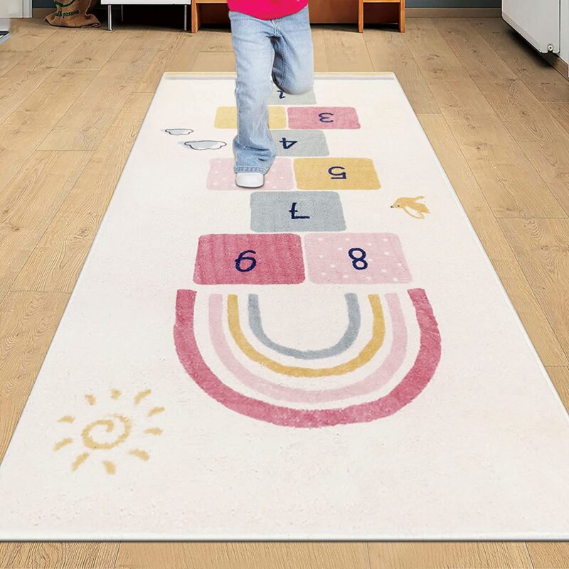 Hopscotch Rug A child is shown from the waist down playing on a hopscotch rug that also has a rainbow on it.