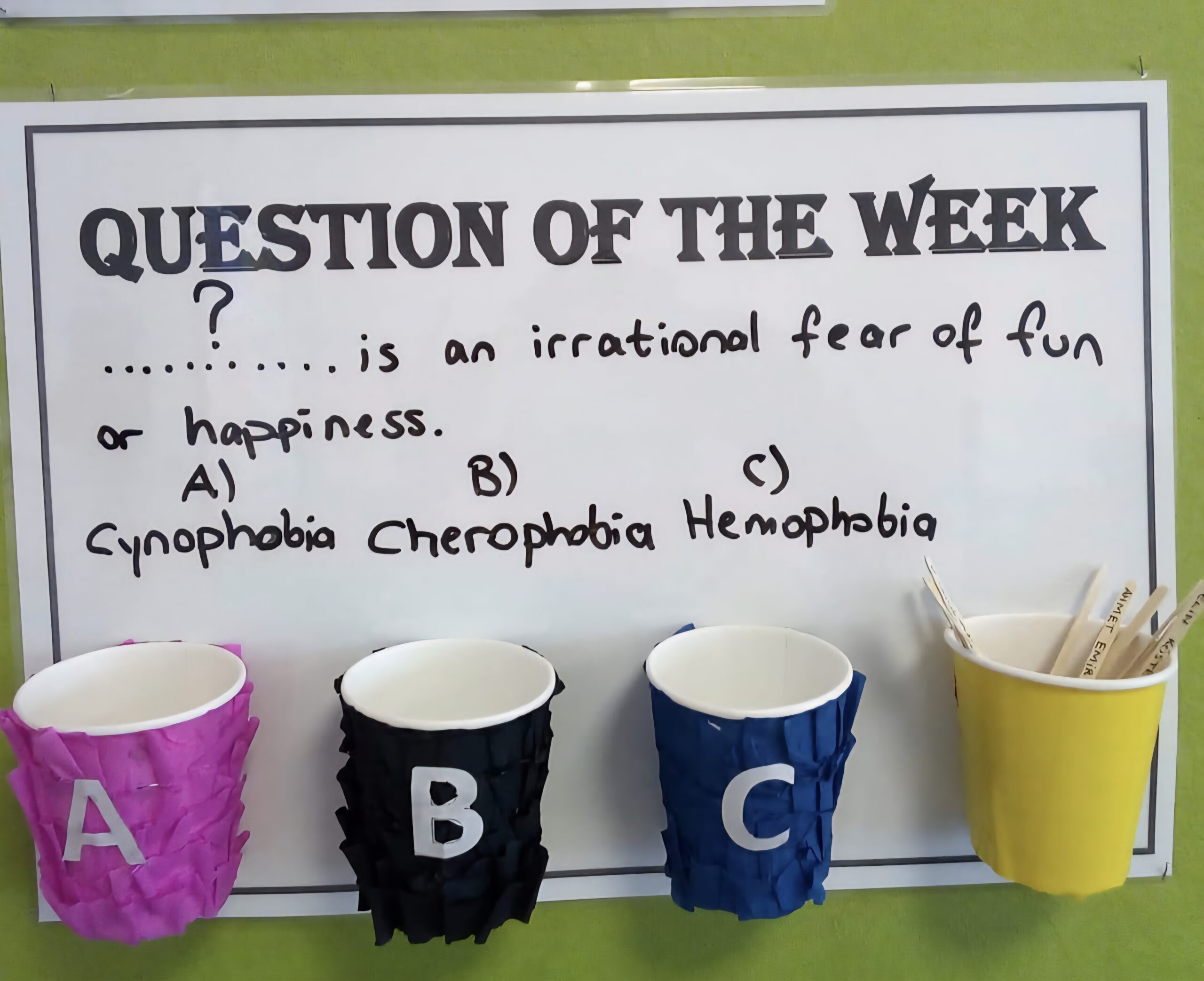 Interactive Bulletin Boards: Question of the Week Question of the Week bulletin board with a vocabulary word multiple choice question and cups for making a guess