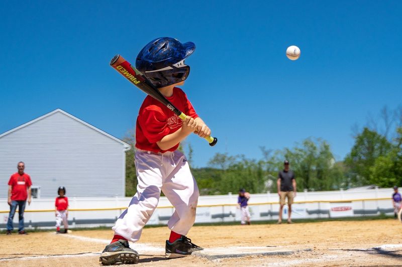 Picture Prompt: Little League Small child waiting at home base for a baseball pitch that's about to arrive