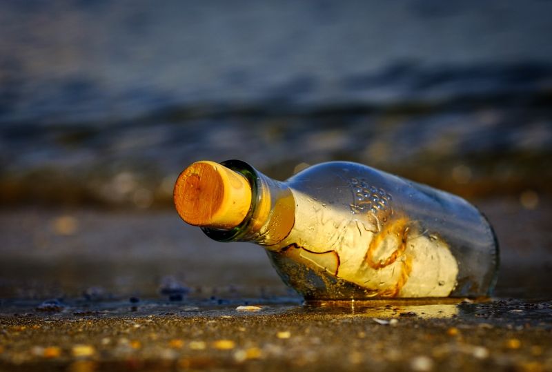 Picture Prompts: Message in a Bottle Glass bottle on a seashore with a rolled up paper inside