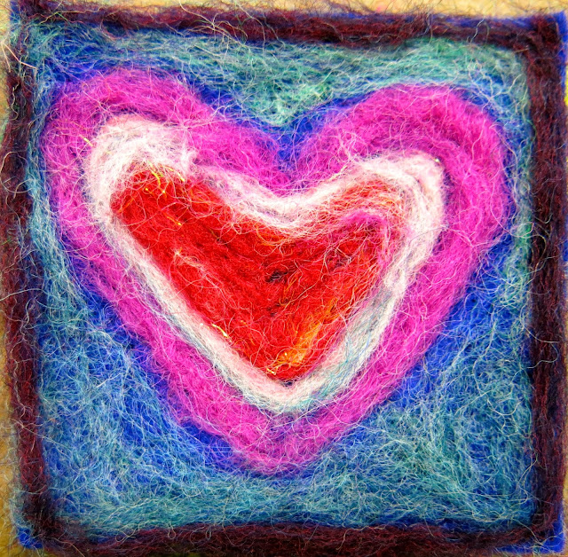 Needle Felted Heart Needle felted heart in pink, white, and red against a blue-green background