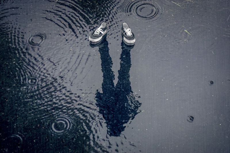 Writing Prompt: Shadows A pair of sneakers and a person's shadow in a puddle