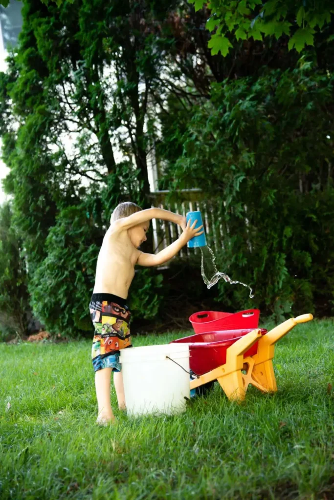 obstacle-course boy pouring water from a bucket into a larger bucket for a water activity