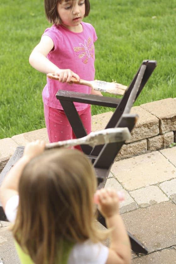 paint-with-water girl painting a chair with a paintbrush and water for a water activity