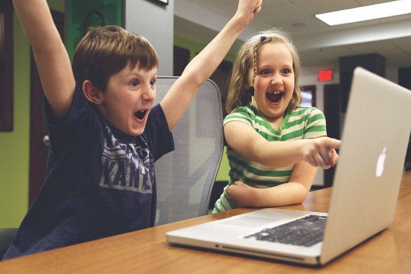 Picture Writing Prompts A young boy raises his arms in triumph as a young girl points at a computer screen, smiling (Picture Writing Prompts)