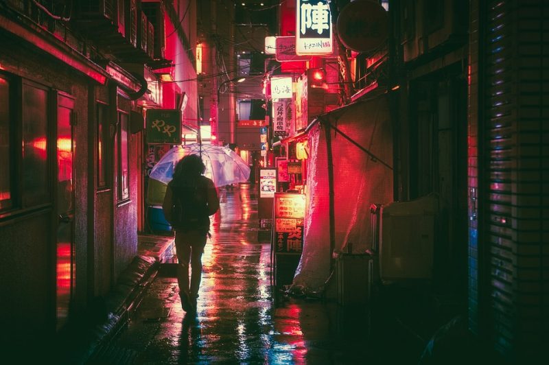 Picture Writing Prompts: Night Lights A person holding an umbrella walks down an alley toward a street filled with neon lights