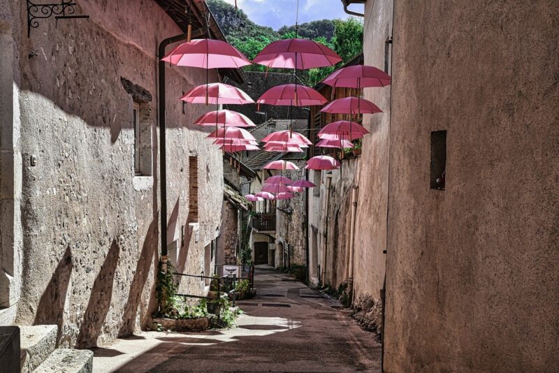Picture Prompts: Pink Umbrellas A sunny alleyway with pink umbrellas strung across it