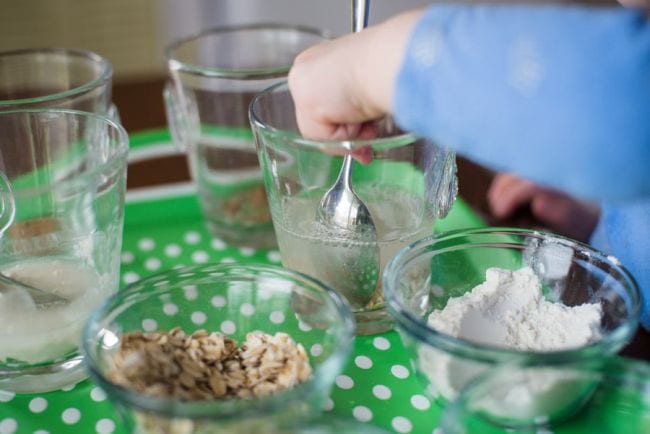 dissolves-in-water Preschool science student mixing various solids into glasses of water