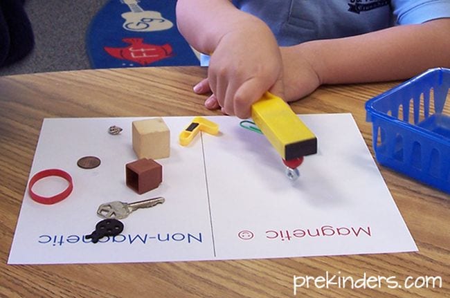 magnet-experiment Preschool science student using a bar magnet to test other objects as an example of science activities for preschoolers