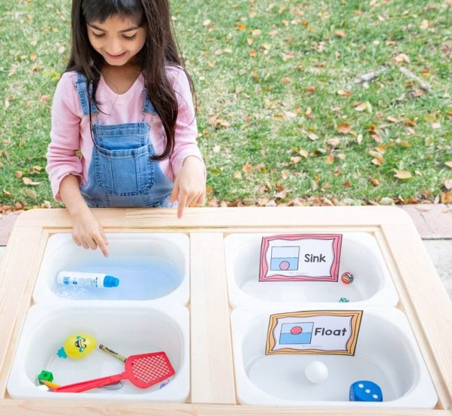 sink-or-float Preschool science student placing objects in bins of water to see if they sink or float