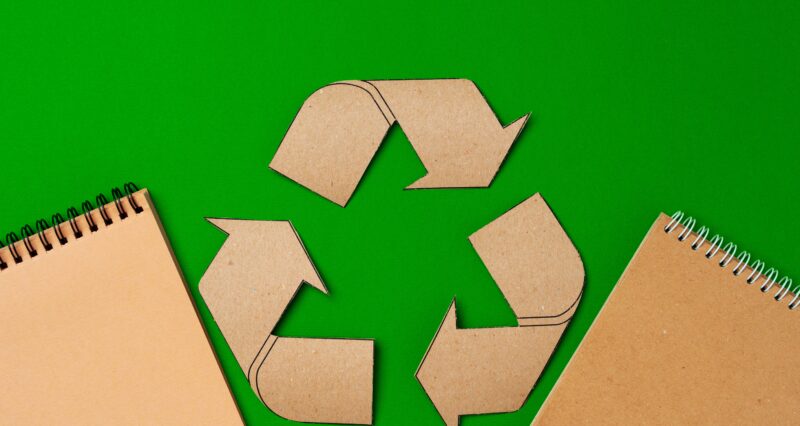 Paper recycling concept on green background top view