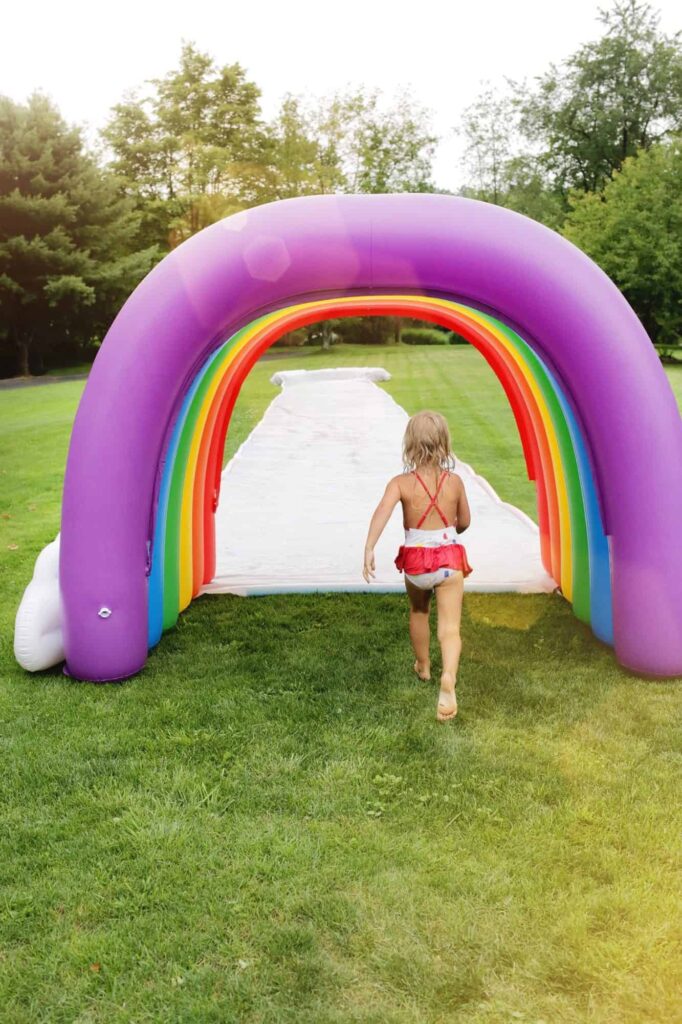 slip-n-slide girl running through a blow up rainbow to a slip n slide for water activity