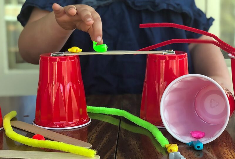 solo-cup-bridge A preschooler constructs a bridge from red solo cups and popsicle sticks as an example of science activities for preschoolers