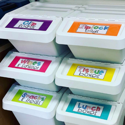 6 bins are stacked with colorful labels on them that read things like clipboards, ziplock bags, etc.