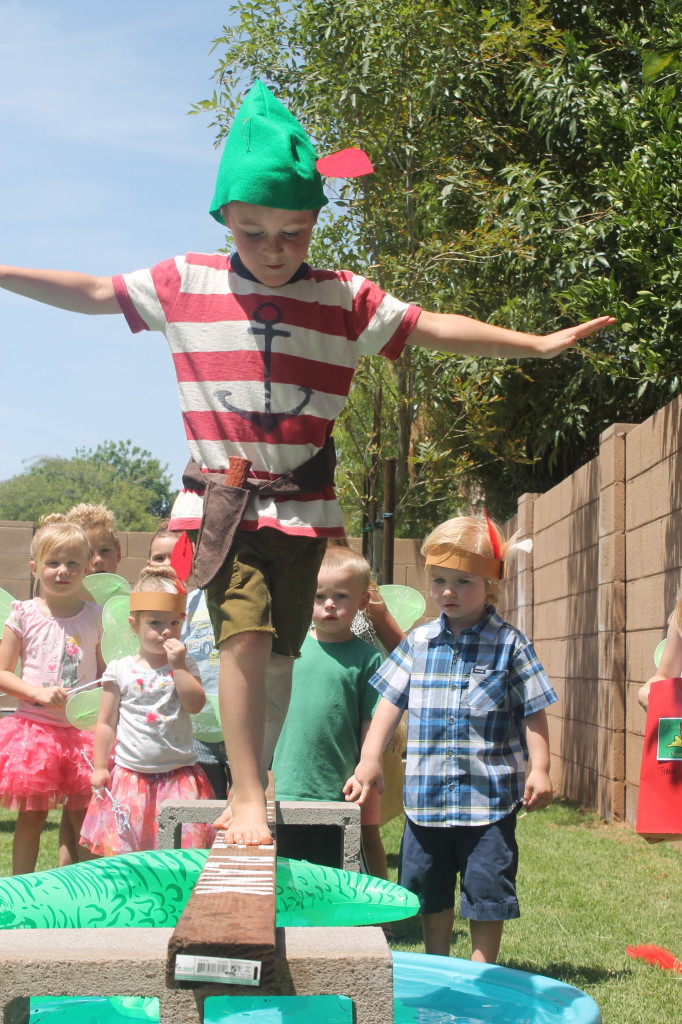 walk-the-plank boy walking across a board that is placed over a kiddie pool for a water activity
